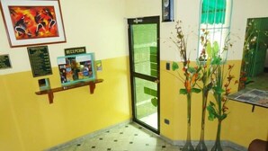 Un'area reception con una scrivania, opere d'arte incorniciate, una bacheca con il menu e una porta in vetro che dà all'esterno.