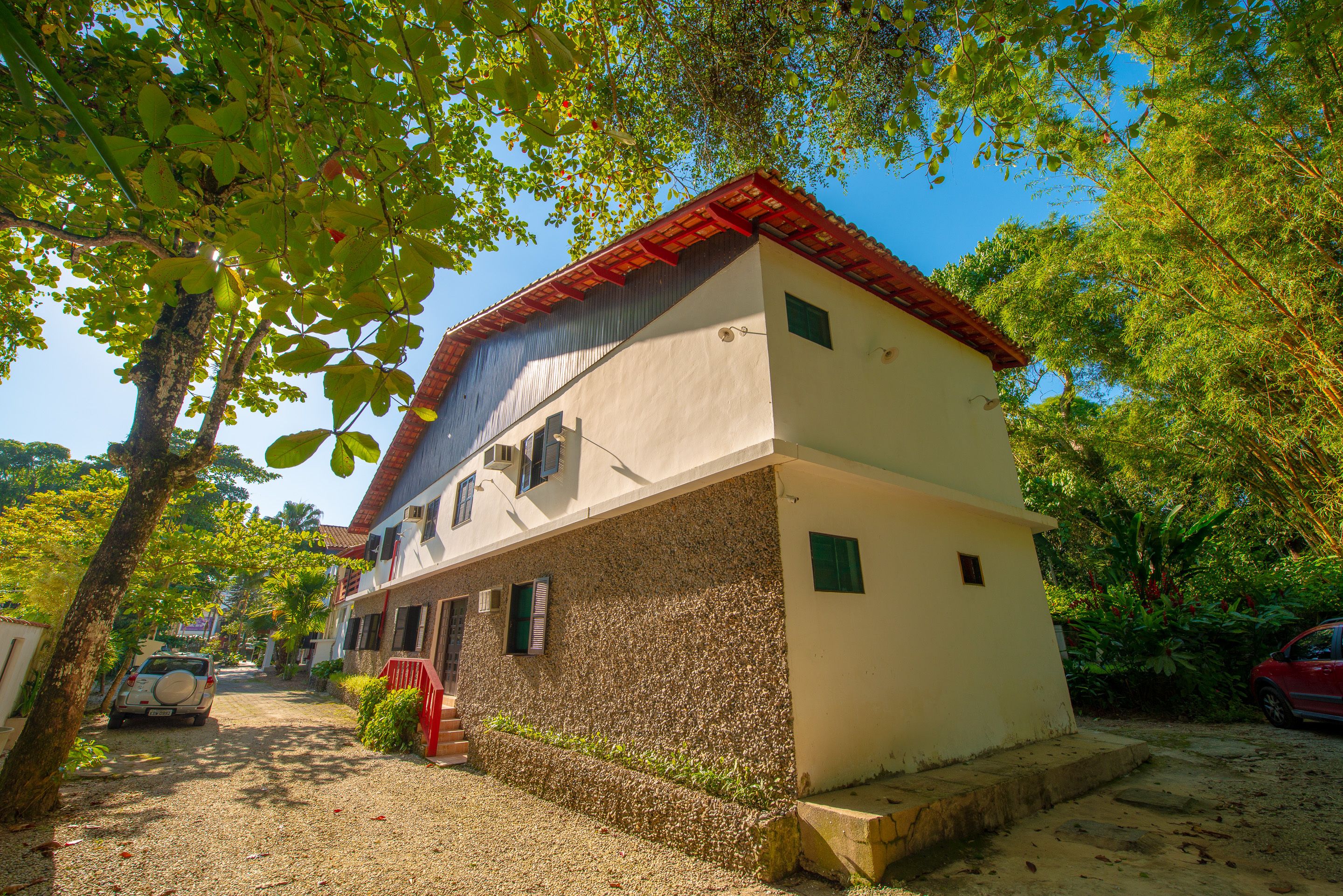 Un bâtiment à deux étages, doté d’un toit recouvert de tuiles rouges, d’une allée en gravier et d’un portail rouge.