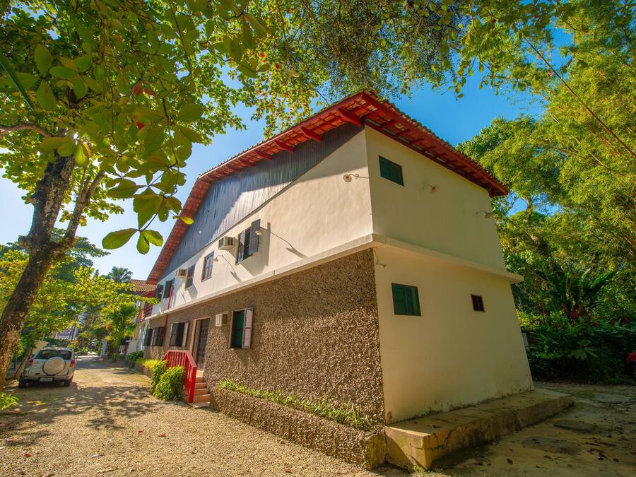 Un bâtiment à deux étages, doté d’un toit recouvert de tuiles rouges, d’une allée en gravier et d’un portail rouge.