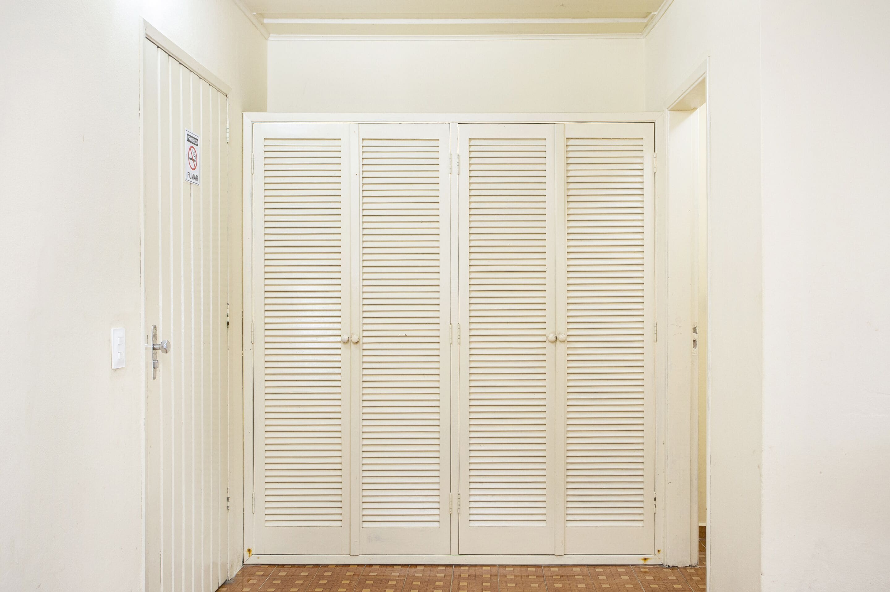 A closed white closet with horizontal louvered doors, a door handle, and a "No Entry" sign on the left door.