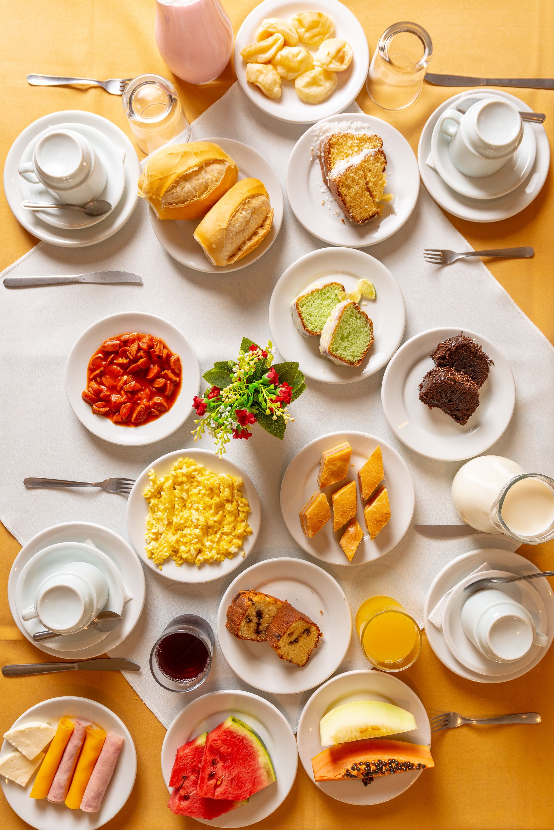 Una mesa de desayuno con diversos platos, incluyendo pasteles, frutas y bebidas.