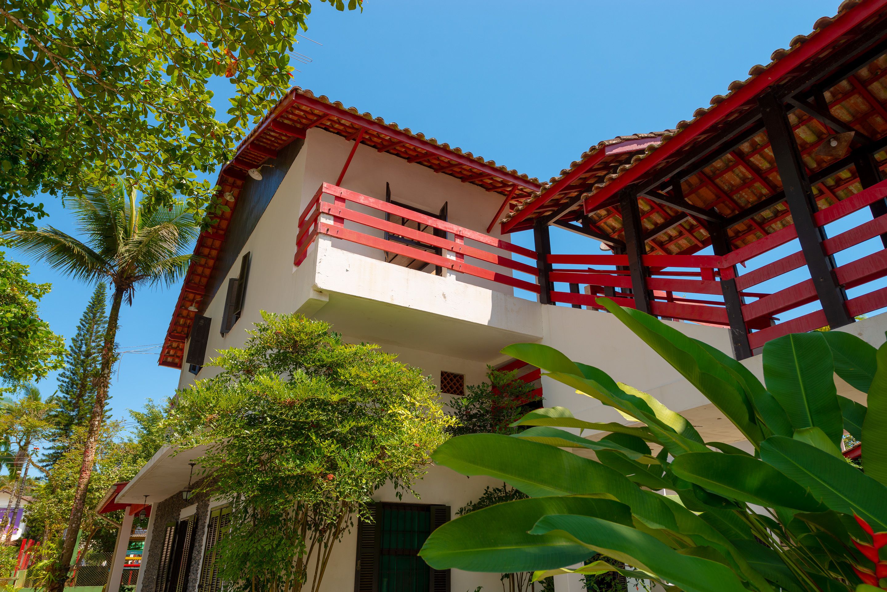 A two-story building with a red balcony and a white facade.