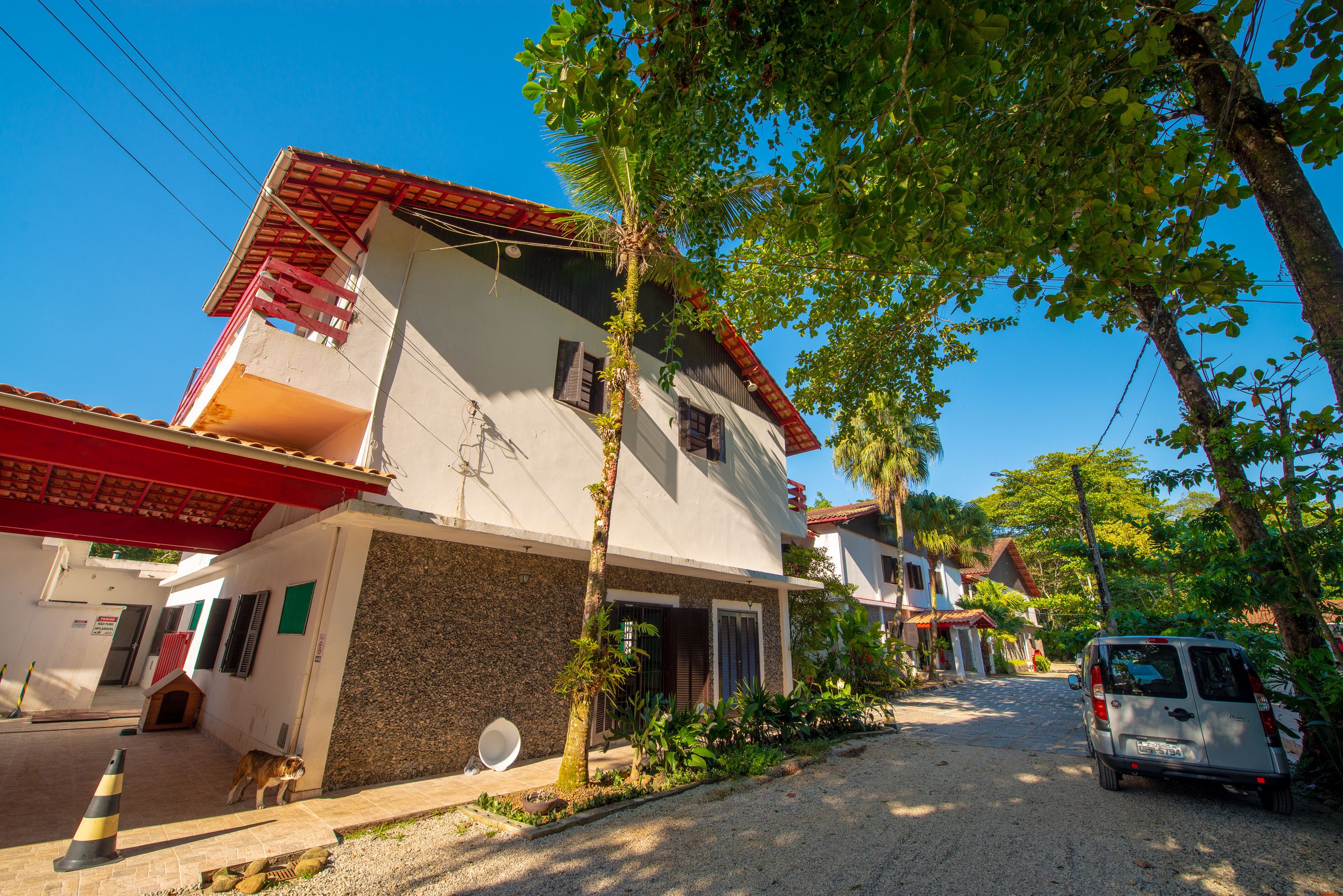 A two-story building with a red roof, a balcony, and a driveway.