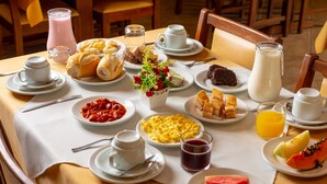 Mesa de café da manhã com diversos pratos, incluindo ovos, torradas e frutas.
