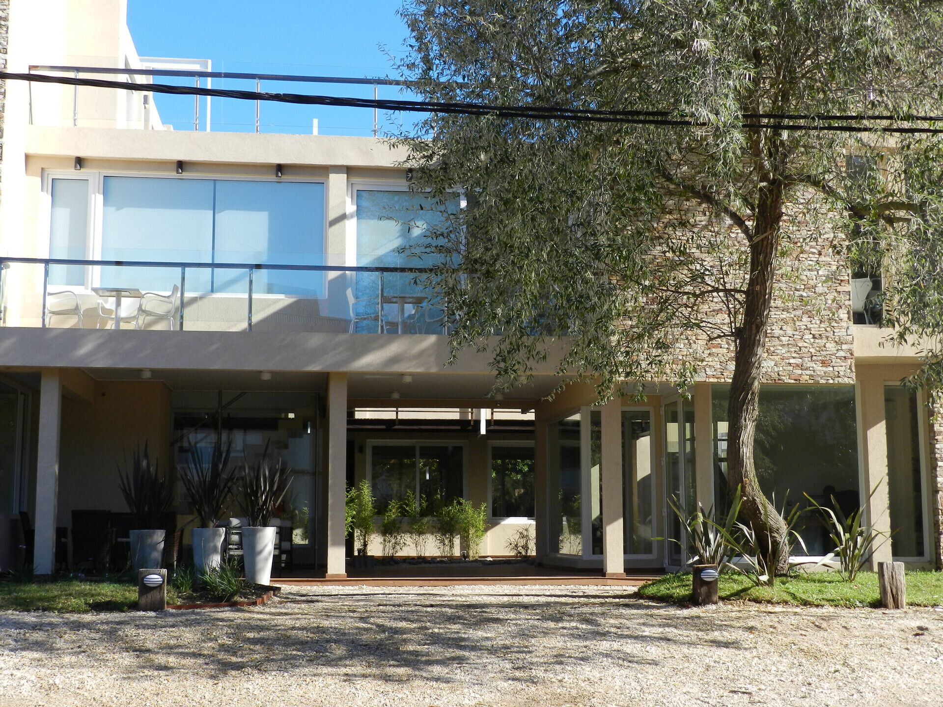 A modern building with a covered entrance, outdoor seating, and potted plants.