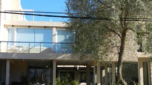 Un edificio moderno con entrada cubierta, ventanas amplias y asientos al aire libre.