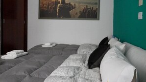 A bedroom with a bed, a framed picture of a beach scene, and a teal wall. - Alma Viva (Mar del Plata)