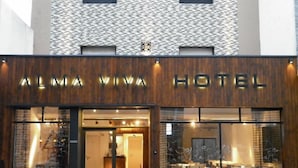 The exterior of the Alma Viva Hotel with a modern design, featuring a wooden facade and large glass windows. - Alma Viva (Mar del Plata)