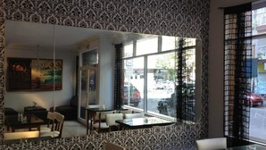 A restaurant with patterned wallpaper, a large mirror, and a view of the street outside. - Alma Viva (Mar del Plata)
