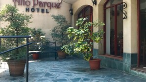 The exterior of Alto Parque Hotel with a stone-paved entrance, potted plants, and a metal railing. - AltoParque Hotel (Salta)