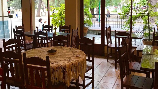 A dining area with large windows, wooden tables, and chairs. - AltoParque Hotel (Salta)