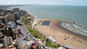 Un paisaje urbano costero con una playa, edificios altos y cielo despejado.