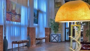 Un vestíbulo con un cuadro grande, un banco, una mesa y una lámpara.