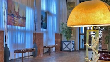 Un vestíbulo con un cuadro grande, un banco, una mesa y una lámpara.