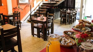 Een restaurant met houten tafels en stoelen, een trap en diverse gerechten op de tafels.