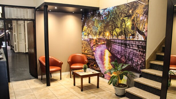 Een lobby met een groot muurschildering, twee leren fauteuils, een kleine tafel en een trap.