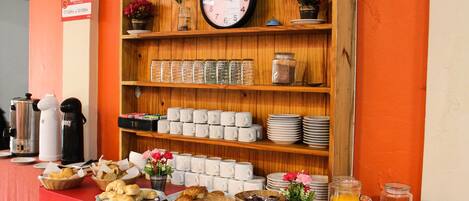 A breakfast buffet with various food items, a clock, and a sign indicating the bar's opening hours.