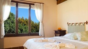 A bedroom with a large bed, a nightstand, and a window with curtains. - Cabañas Puerto Delfín (Mar de las Pampas)