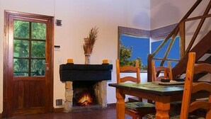 A room with a fireplace, wooden furniture, and a view through a window. - Cabañas Puerto Delfín (Mar de las Pampas)