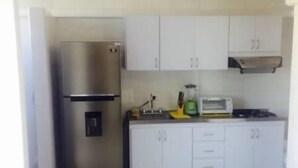 A kitchen with white cabinets, a stainless steel refrigerator, a microwave, and a stove. - Edificio 7 Mares Apto 504 (Santa Marta)