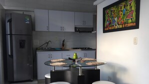 A modern kitchen with a glass-top table, four black stools, and a refrigerator. - Edificio 7 Mares Apto 504 (Santa Marta)