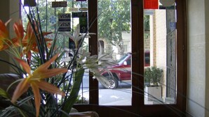 A hotel entrance with a glass door, various signs including a Visa sign, and a red car parked outside. - Hotel Sousas (Mar del Plata)