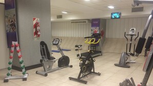 A gym with various exercise equipment including treadmills, stationary bikes, and weight machines. - Intersur Hotel 13 de Julio (Mar del Plata)