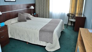 A hotel room with a large bed, a wooden headboard, a desk, a chair, and a nightstand. - Intersur Hotel 13 de Julio (Mar del Plata)