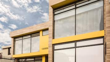 Un edificio moderno con amplios ventanales y una pared de acento amarilla.