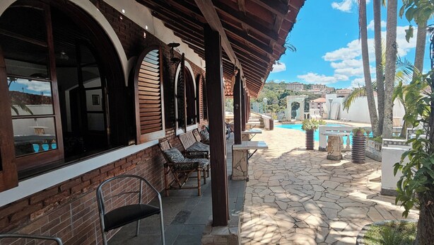 A covered outdoor area with a pool, stone flooring, and seating. - Hotel Pousada Casarão (Serra Negra)