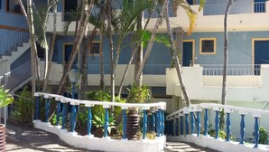 A multi-story building with blue and white exterior walls, a white staircase with blue balusters, and several palm trees. - Hotel Pousada Casarão (Serra Negra)