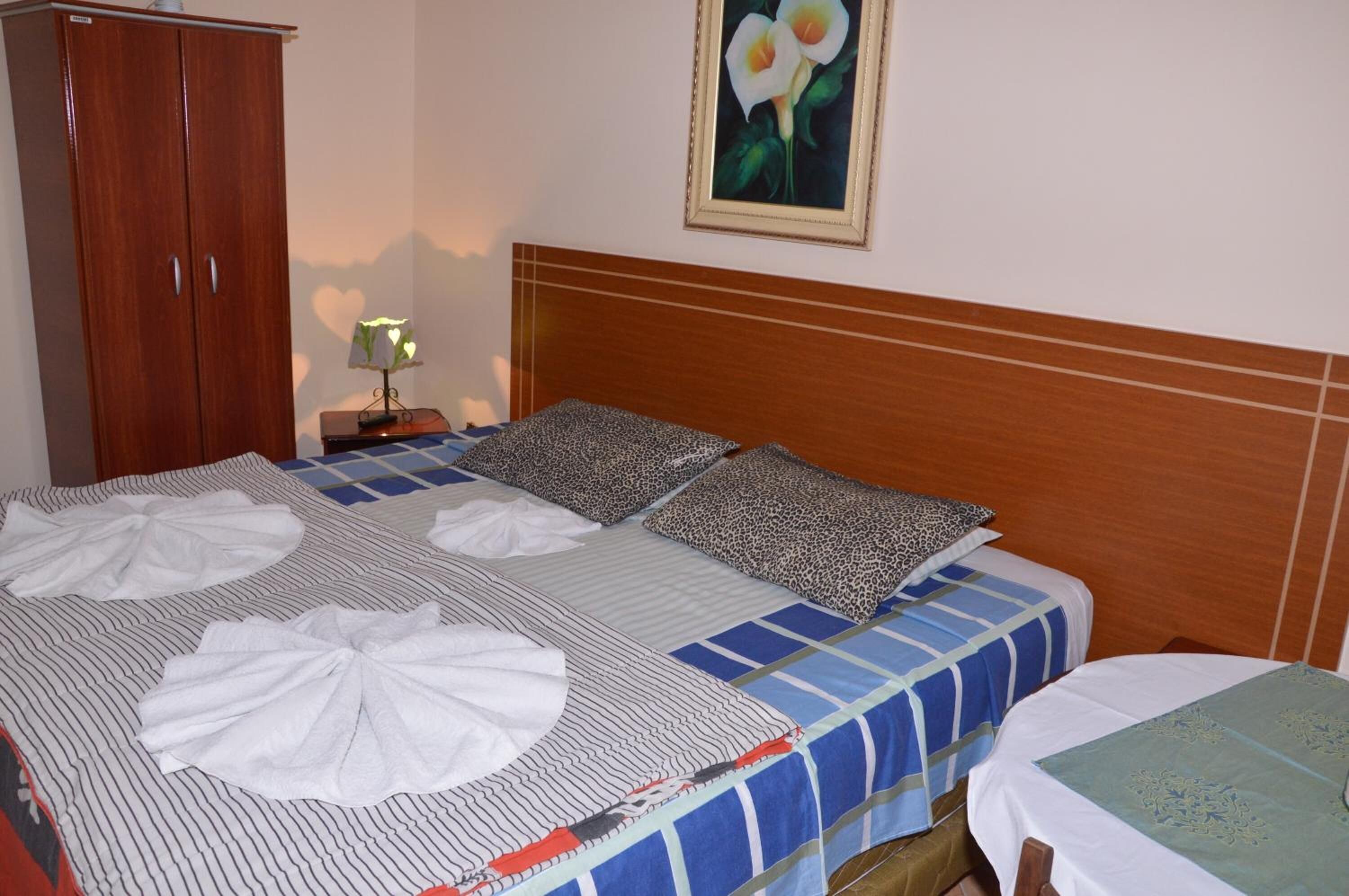 Ein Hotelzimmer mit Bett, einem Holzschrank, einem Nachttisch mit Lampe und einem Bild an der Wand.