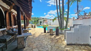 A stone patio with outdoor seating, a swimming pool, and a view of a cityscape. - Hotel Pousada Casarão (Serra Negra)