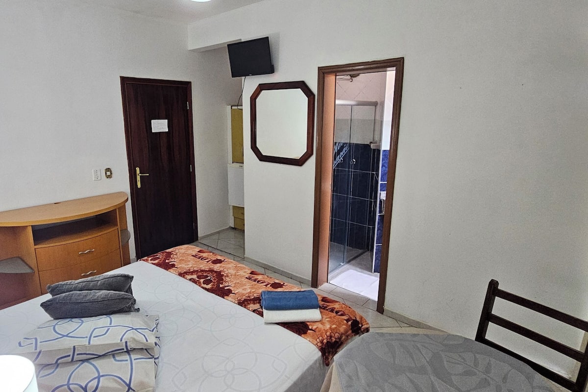 Une chambre d’hôtel comprenant un lit, un bureau, un miroir et un espace douche.