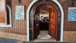 A brick building with a wooden door, two maps on the walls, and a small rug on the floor. - Hotel Pousada Casarão (Serra Negra)