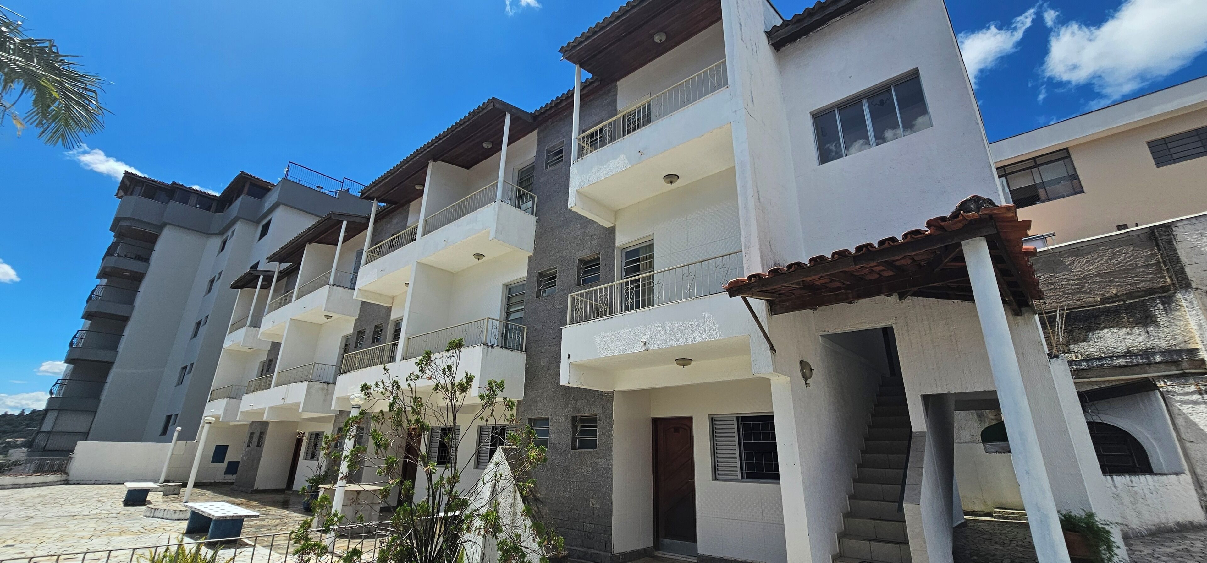 A multi-story residential building with balconies, a staircase, and a small garden area.