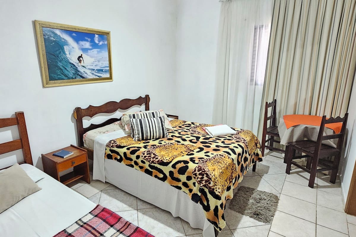 Une chambre à coucher avec un lit, des tables de chevet, une chaise, un tableau et des rideaux.