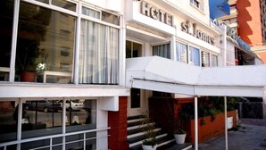 Un hotel con fachada blanca, ventanas grandes y entrada cubierta.