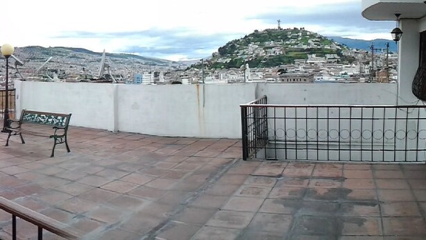 A rooftop terrace with a tiled floor, a small tree, and several benches. - El Fundador Apartamento (Quito)