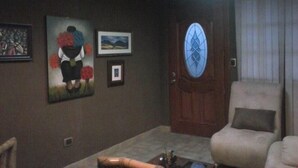 A living room with a beige armchair, a coffee table, and a door with a stained glass window. - El Fundador Apartamento (Quito)
