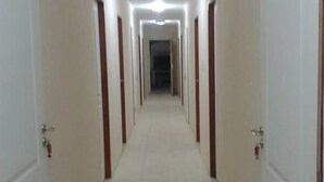 A long, narrow hallway with white walls and doors on both sides, leading to a dark room at the end. - Mar del Faro (Mar del Plata)