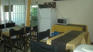 A compact kitchen with a refrigerator, microwave, and a table set for dining. - Mar del Faro (Mar del Plata)