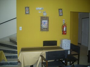 Ein Essbereich mit gelber Wand, einem Feuerlöscher und einem Tisch mit Stühlen.