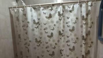 Un baño con cortina de ducha estampada con un diseño de mariposas, un lavamanos y dos inodoros.