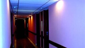 Un pasillo estrecho con suelo de baldosas y paredes pintadas de un tono lila claro.