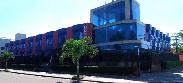 A modern hotel with a prominent glass facade, a red and blue color scheme, and a sign indicating it is a hotel. - Hotel Santamaria (Guarujá)