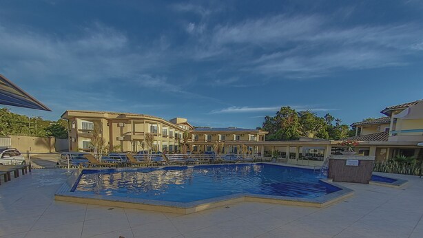 A pool area with a large rectangular pool, lounge chairs, and a building with multiple balconies. - Pontal Praia Hotel (Porto Seguro)