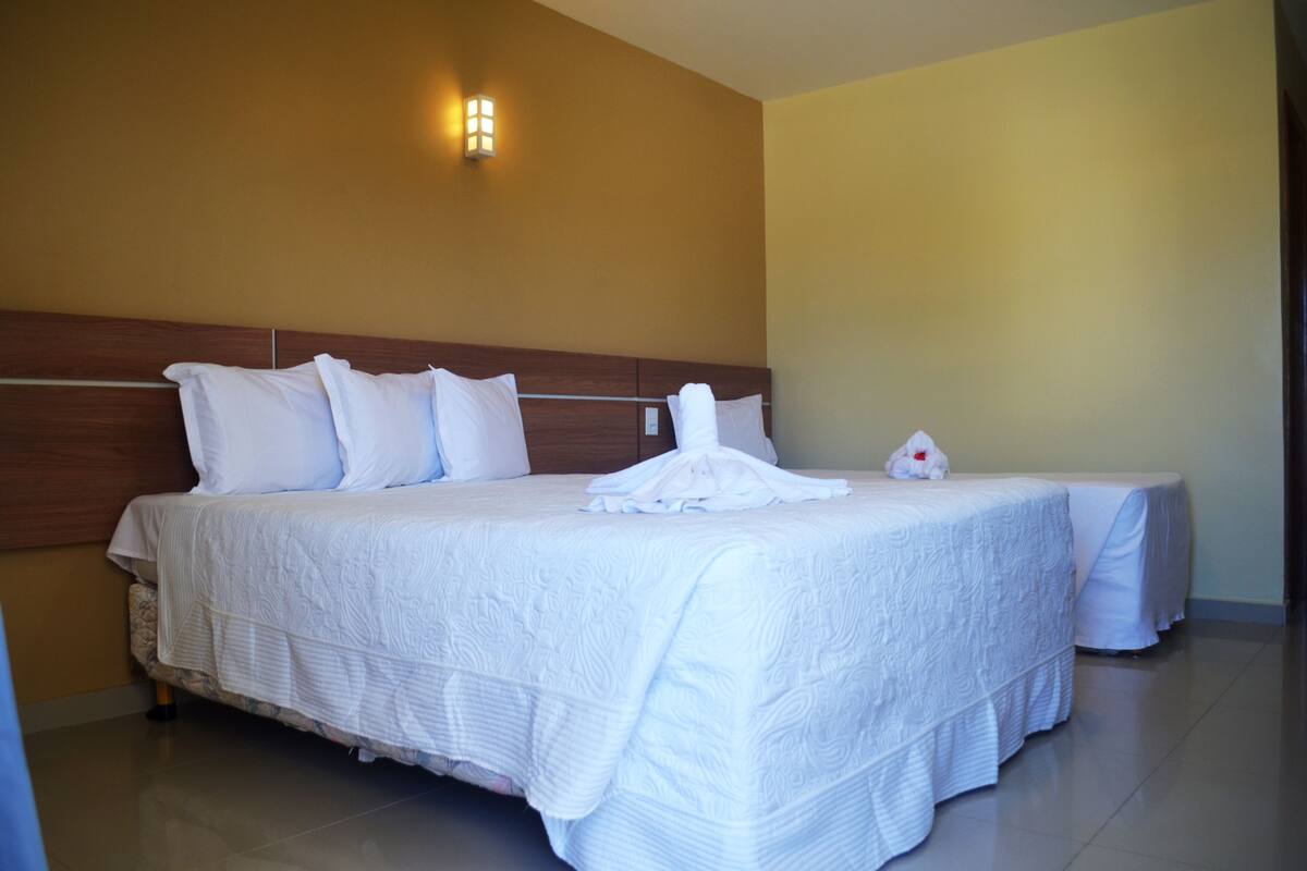 A hotel room with a large bed, a wooden headboard, and a wall-mounted light fixture.