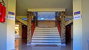 A hotel lobby with a marble staircase, fire extinguisher, and signs indicating room numbers. - Pontal Praia Hotel (Porto Seguro)