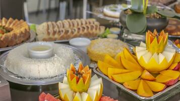 Ein Buffet mit verschiedenen Speisen, darunter Reis, Mangostücken und anderem Obst.